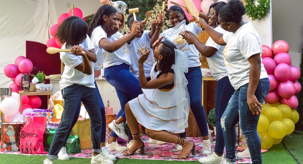 Joyful bridal party with friends gathering for bachelorette celebration outdoors, filled with laughter and playful antics.